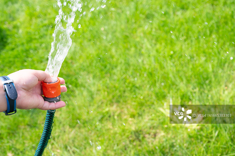 夏日花园里用软管玩水的男孩图片素材