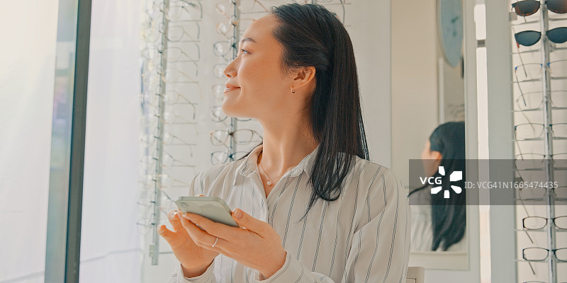 女士在眼镜店使用手机进行社交，咨询眼科保健图片素材