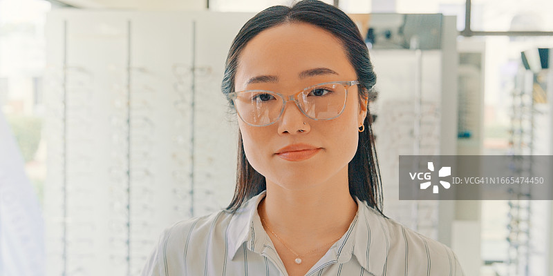 戴眼镜的亚洲女性在眼镜店选购镜框，关注视力健康图片素材