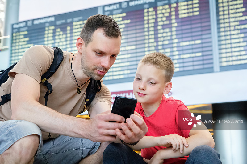 旅行的父子在机场候机时使用手机图片素材
