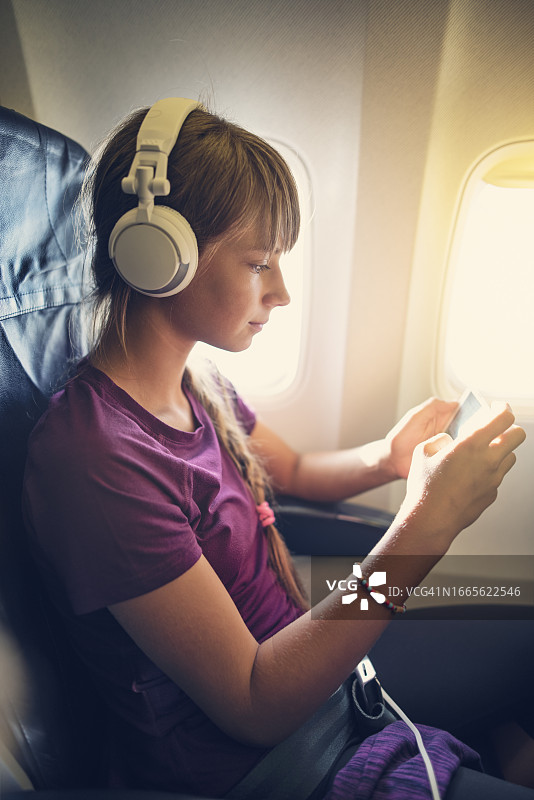 在飞机上使用智能手机的少女图片素材