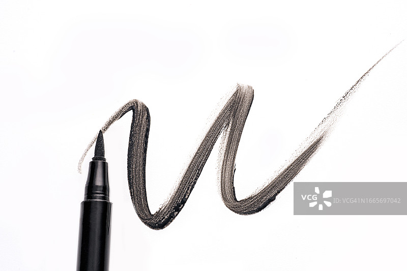 白色背景上黑色眼线笔或眉笔的波浪形黑色污迹，已隔离。眼睛和睫毛的化妆品图片素材
