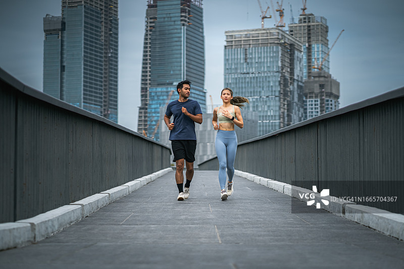 亚洲情侣在首都城市公园里慢跑，都市生活方式理念，锻炼，保健图片素材