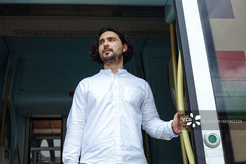 穿着白色衬衫的棕发绅士站在候车门口图片素材