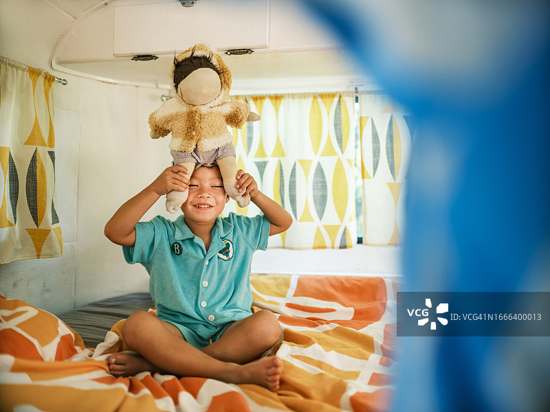 亚洲母亲和儿子在露营车内的床上玩耍图片素材