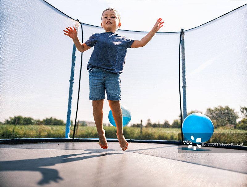 混血男孩在夏天玩蹦床图片素材