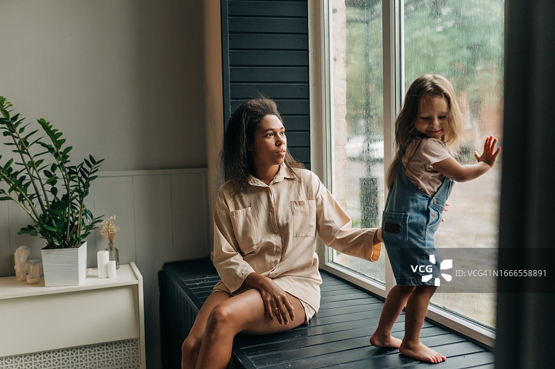混血母亲和女儿坐着向窗外看图片素材