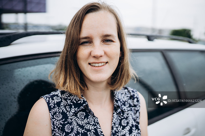 一位在街上汽车旁的年轻微笑女性的肖像图片素材