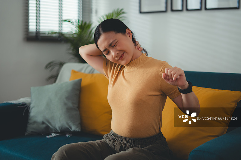 在家中客厅沙发上颈椎疼痛的亚洲女人图片素材