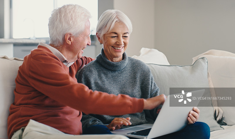 在客厅沙发上浏览社交媒体的老年夫妇图片素材