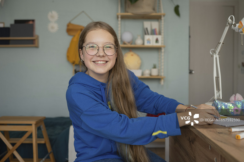 戴眼镜的微笑女孩在桌旁图片素材