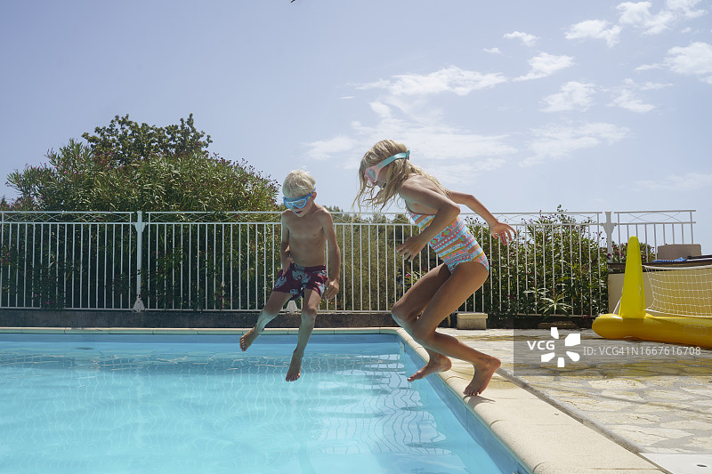 在游泳池里跳跃的快乐兄妹图片素材