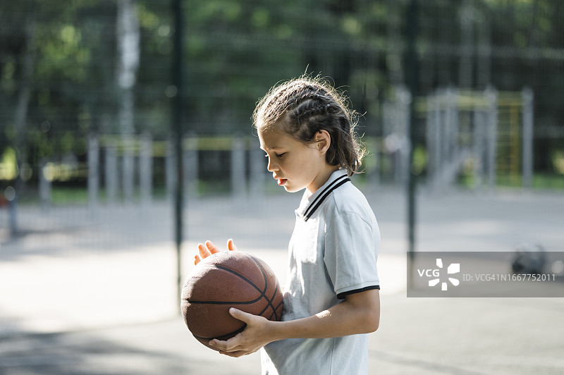 男孩在运动场上拿着篮球图片素材