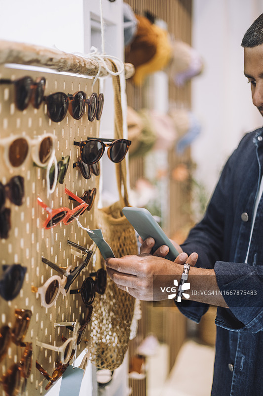 男人在时装店的货架上拍摄太阳镜的标签图片素材
