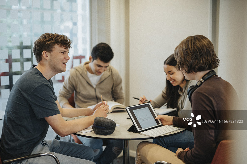 快乐的年轻学生在大学里一起在桌旁学习讨论图片素材