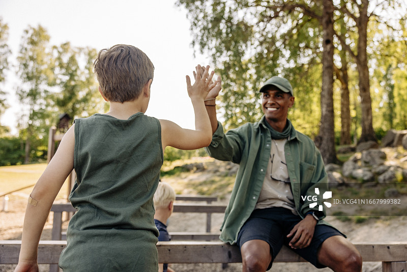 夏令营期间，男孩与男辅导员击掌的背影图片素材
