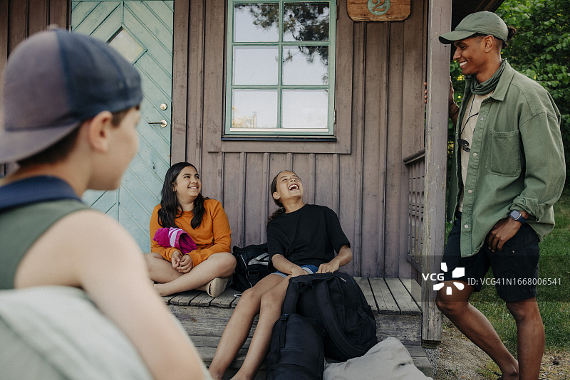 女孩们在夏令营的小屋旁与辅导员交谈时大笑图片素材