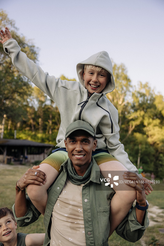 男辅导员在游乐场肩上扛着快乐的男孩图片素材