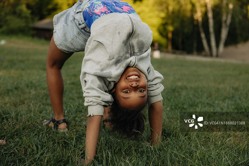 操场草地练习下腰的微笑女孩图片素材