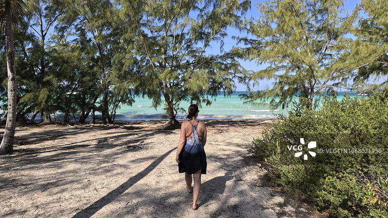 女人沿着通往海滩的沙路行走图片素材