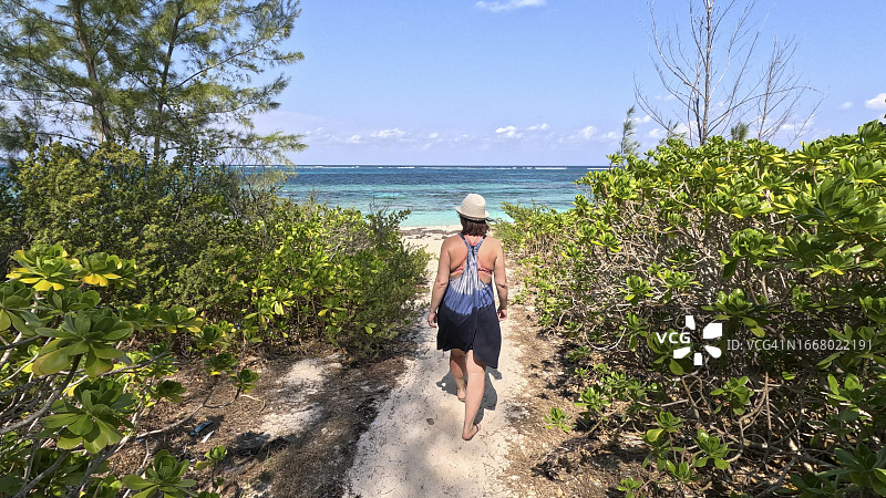 女子走在通往大海的沙滩小路上图片素材