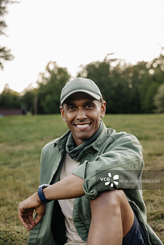 坐在操场上戴着帽子的快乐男人肖像图片素材
