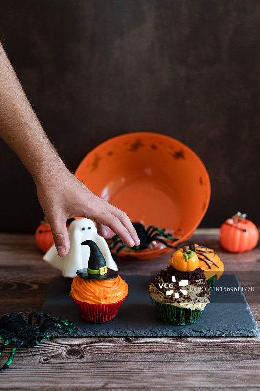 手拿巫婆帽和南瓜纸杯蛋糕图片素材