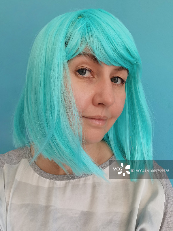 戴着绿松石色长款波波头假发的中年妇女（40-44岁）的自画像，未来主义风格的狂欢节服装图片素材