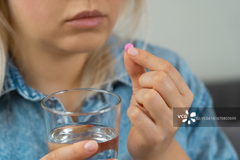 女子用水杯送服药丸。药丸、药物、维生素图片素材