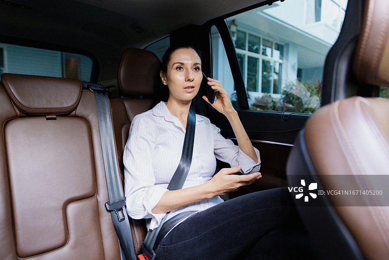 成年人在豪华出租车后座使用数码设备图片素材