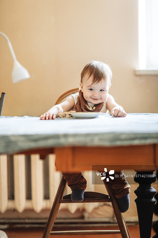 在婴儿餐盘旁享受食物的微笑婴儿图片素材