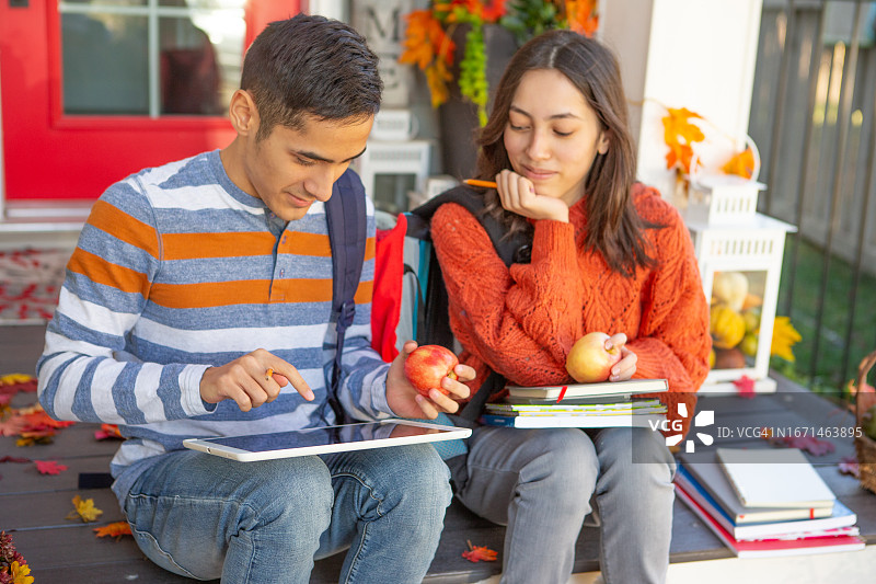 快乐的青少年兄妹一起看笔记图片素材