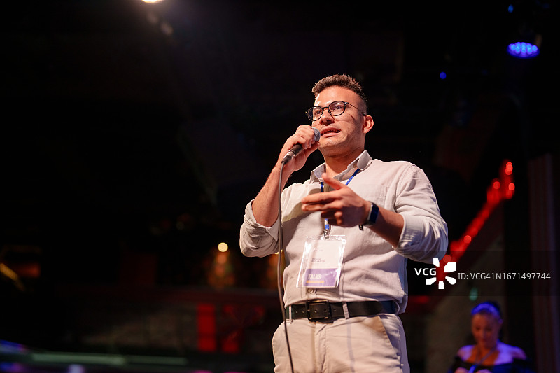 演讲者在舞台上用麦克风向观众做演示图片素材