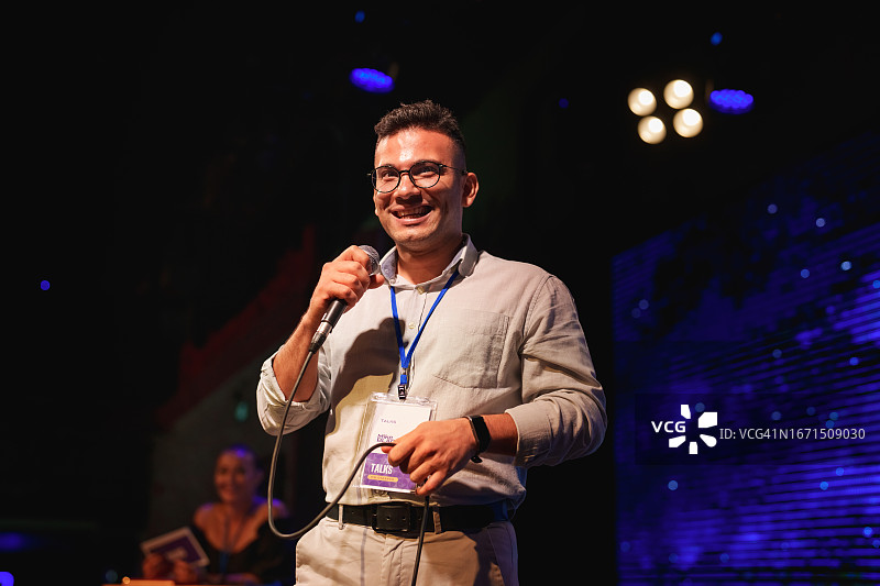 演讲者在舞台上用麦克风向观众做演示图片素材