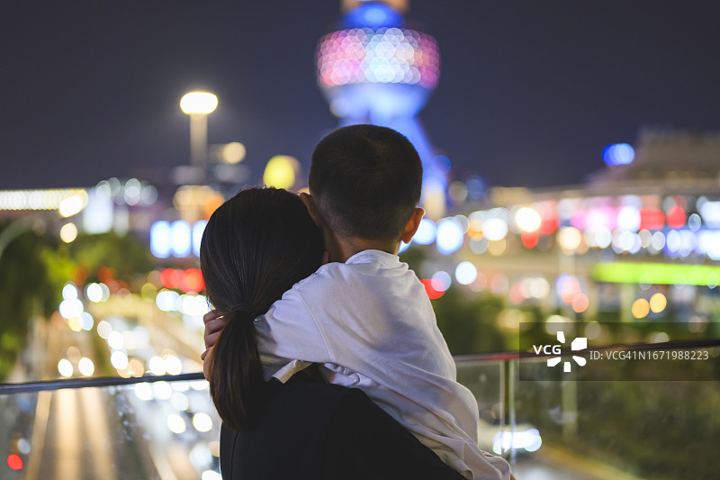 母亲和儿子一起观看城市夜景，亲子旅行图片素材