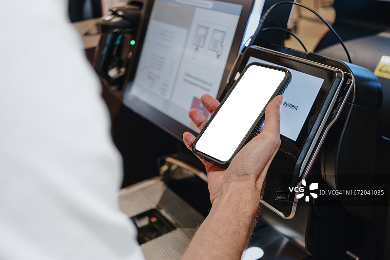 男人在自助结账机前用智能手机购物图片素材