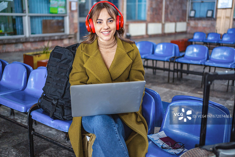 在车站等候时使用笔记本电脑的年轻女人图片素材