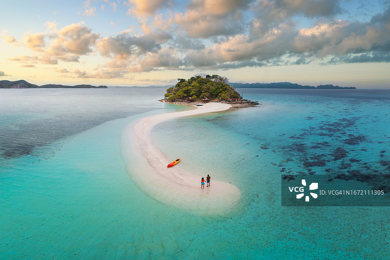 日落时在田园诗般的热带沙洲上的情侣图片素材