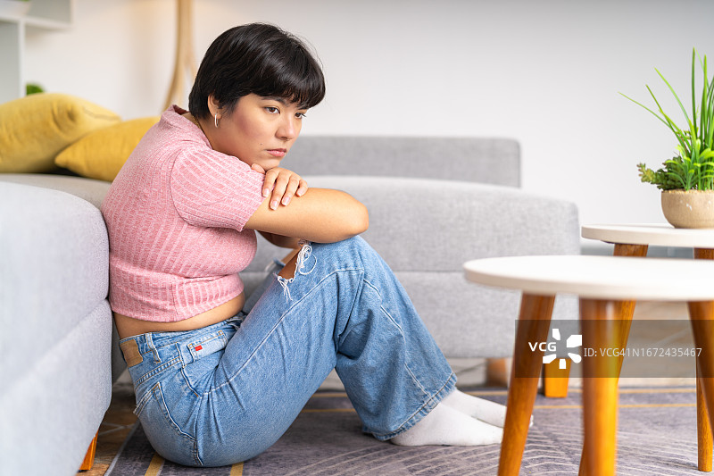 坐在客厅地板上的沮丧妇女图片素材