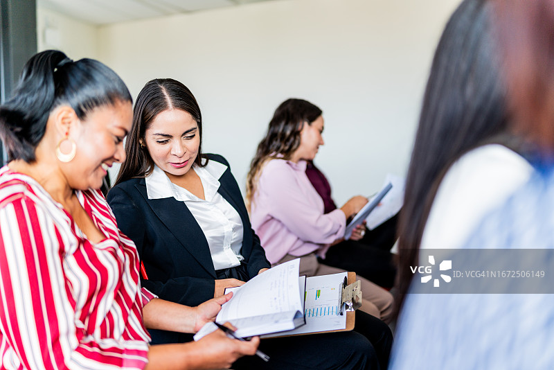 同事们在办公室开会时查看文件并交谈图片素材