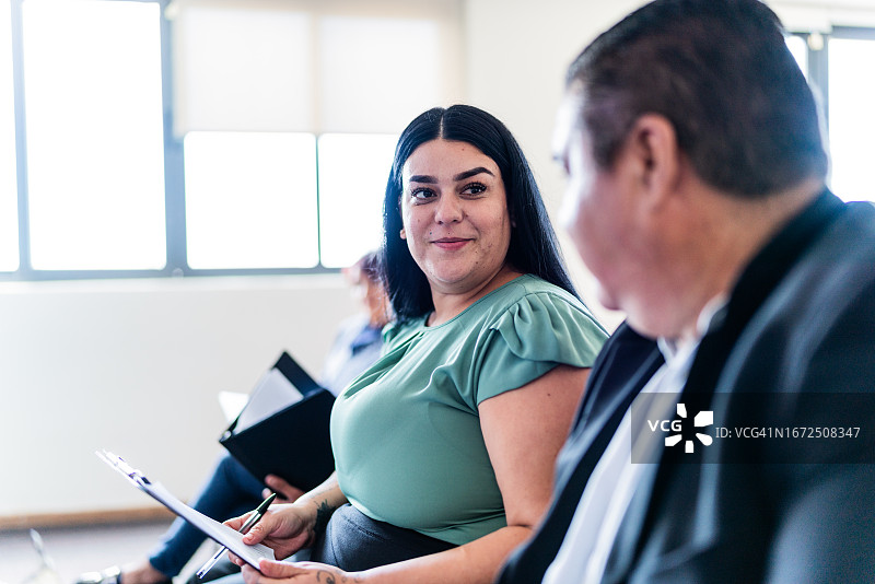 在办公室研讨会期间与同事交谈的中年女商人图片素材