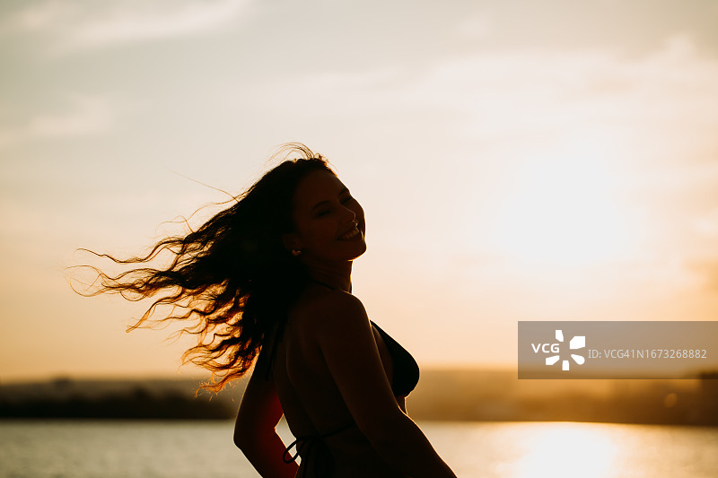 留着棕色长发、在海滩上转身面对镜头的美丽女士照片图片素材
