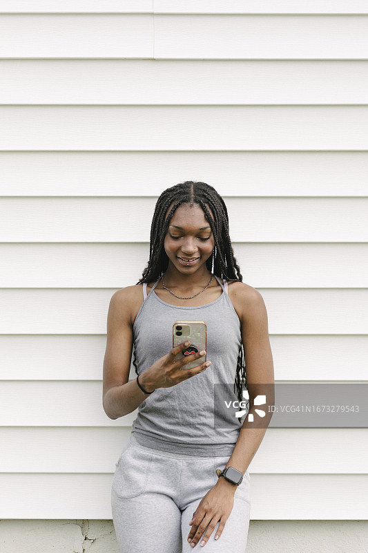 穿运动裤和露脐装看智能手机的女人图片素材