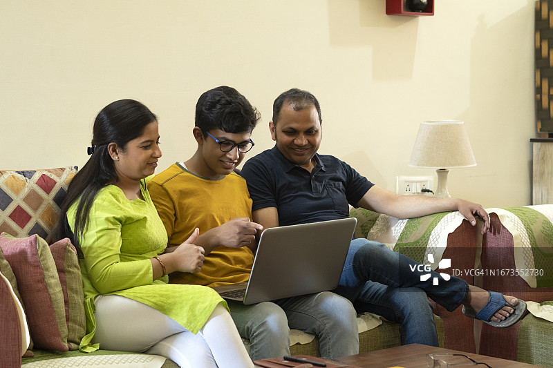 家人坐在沙发上使用笔记本电脑图片素材