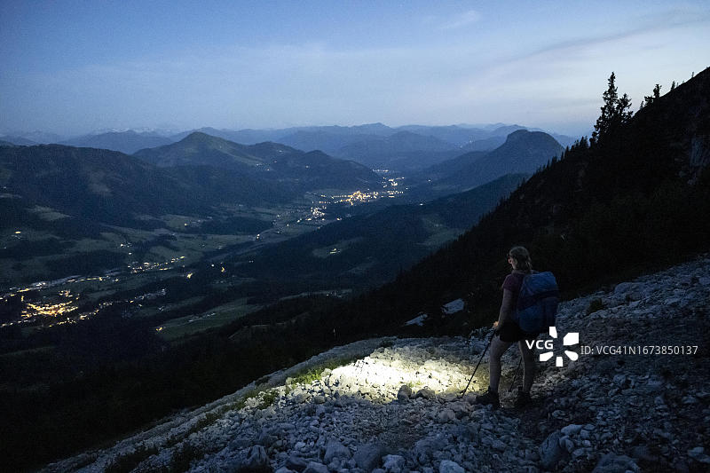 女性登山者在夜晚用火炬徒步旅行，奥地利蒂罗尔凯撒山图片素材