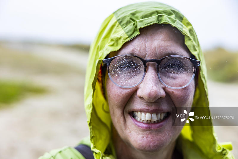 在法国诺曼底芒什科唐坦地区，穿着雨衣、戴着沾满雨滴的眼镜，在海边散步后浑身湿透的女人图片素材