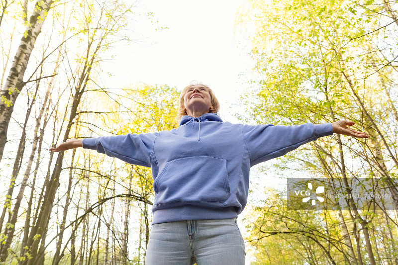 中年女人张开双臂享受大自然图片素材