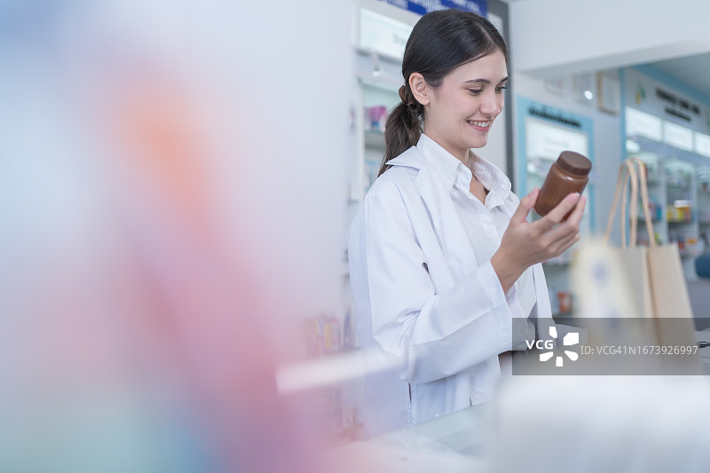 女药剂师为顾客检查瓶装药品图片素材