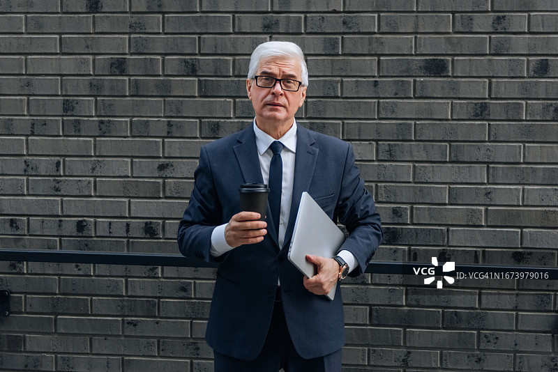 手持咖啡和笔记本电脑的商务男人像图片素材