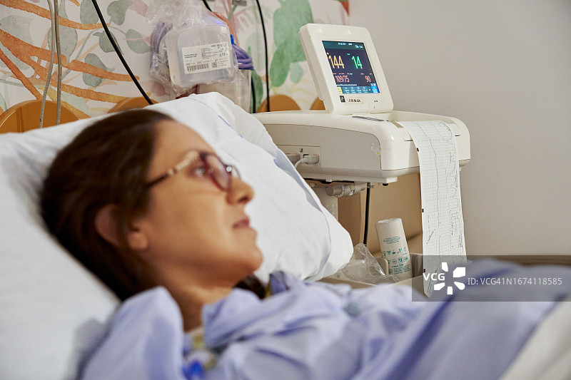 女子躺在床上，靠近胎心监护仪图片素材